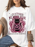 Women's Breast Cancer Awareness T-Shirt- Black With Pink Ribbon And "In October We Wear Pink" Slogan, Short Sleeve Round Neck Casual Top, Designed With Pink Cat And Pumpkin Lantern